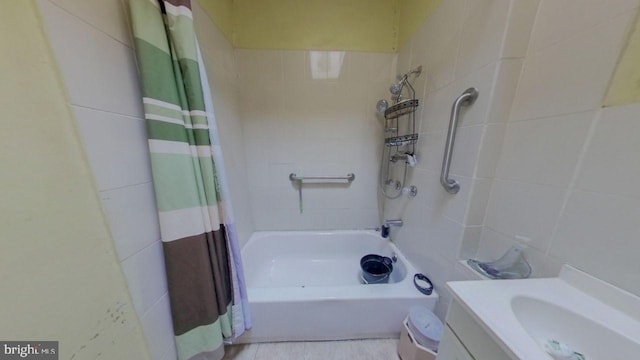 bathroom with vanity, shower / bathtub combination with curtain, and tile walls