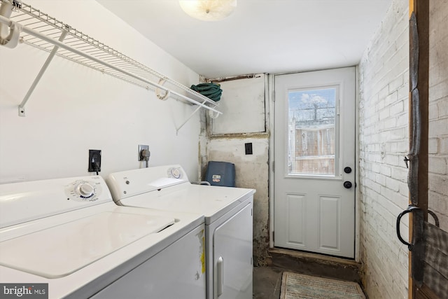 laundry room with washing machine and clothes dryer and brick wall