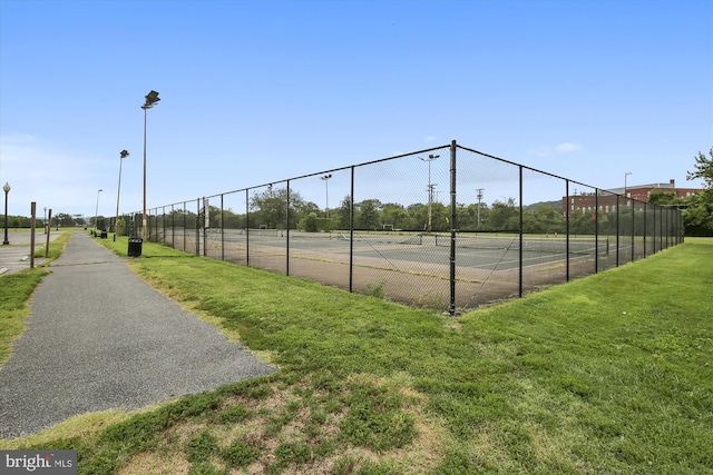 view of tennis court with a yard