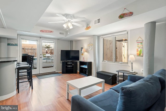 living room with a ceiling fan, visible vents, light wood finished floors, and baseboards