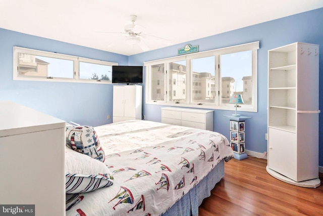 bedroom with ceiling fan, baseboards, and wood finished floors