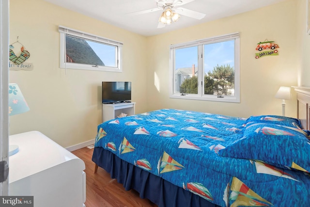 bedroom featuring a ceiling fan, baseboards, and wood finished floors