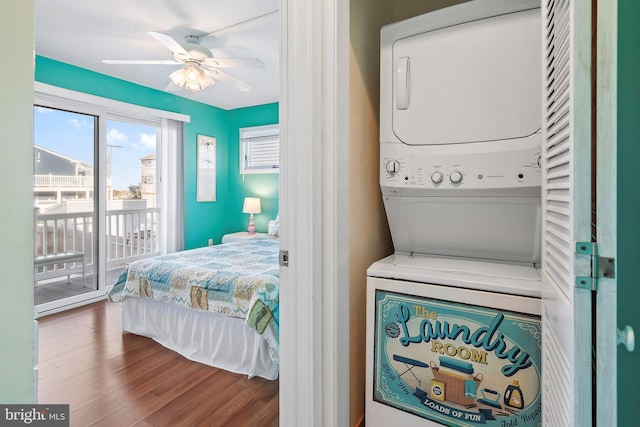 laundry area featuring laundry area, wood finished floors, stacked washer and clothes dryer, and ceiling fan