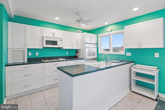 kitchen with white appliances, white cabinets, and a sink