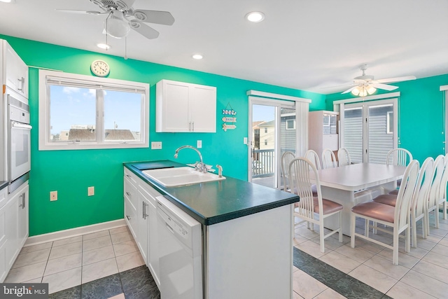 kitchen featuring white appliances, white cabinets, a ceiling fan, and a sink