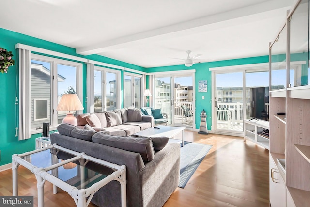 living area with beamed ceiling, wood finished floors, baseboards, and ceiling fan