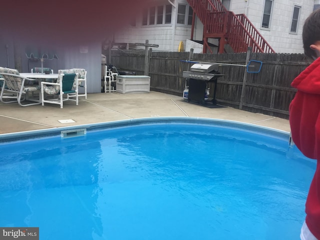 view of pool with a patio area, grilling area, a fenced in pool, and fence