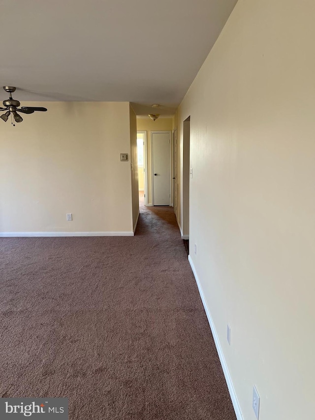 spare room featuring ceiling fan and dark carpet