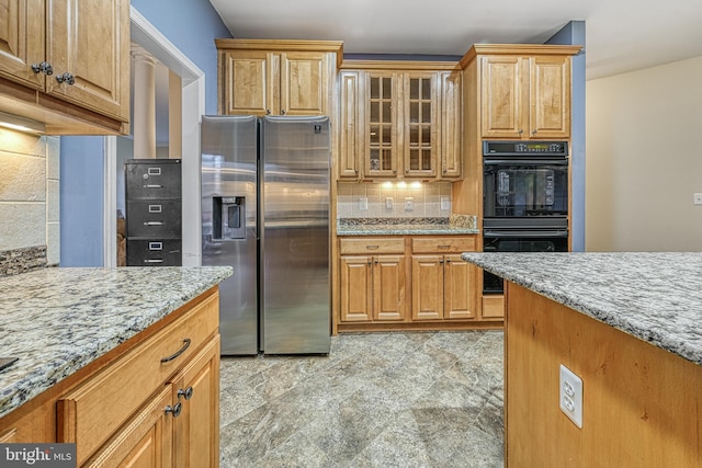 kitchen featuring double oven, decorative backsplash, light stone countertops, and stainless steel refrigerator with ice dispenser