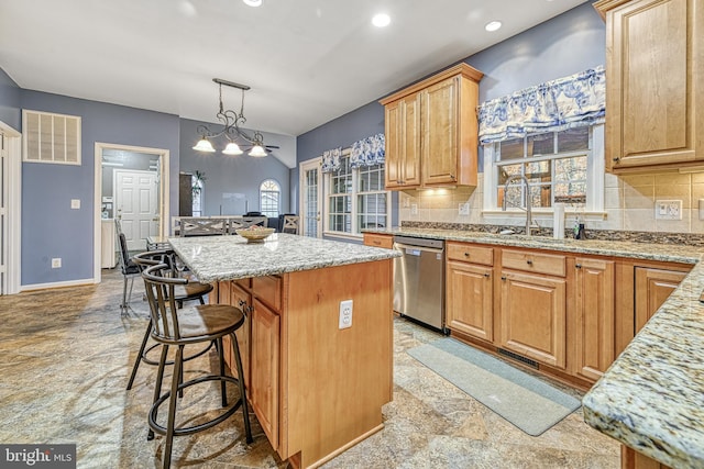 kitchen featuring backsplash, sink, decorative light fixtures, dishwasher, and a kitchen island