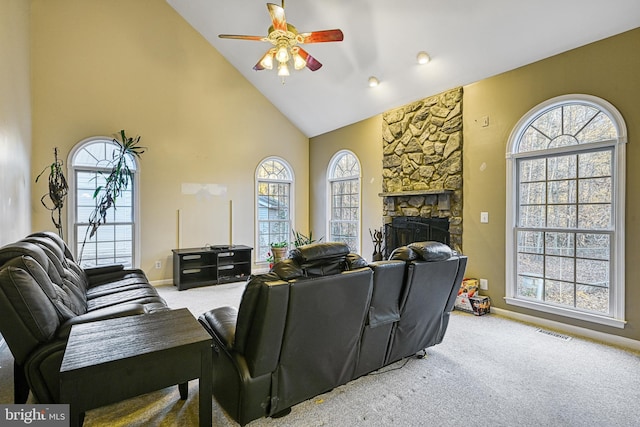 carpeted living room with high vaulted ceiling, ceiling fan, and a stone fireplace