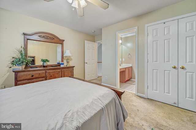 carpeted bedroom featuring a closet, ensuite bath, and ceiling fan