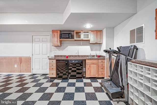 kitchen featuring sink, light brown cabinets, beverage cooler, wooden walls, and black appliances