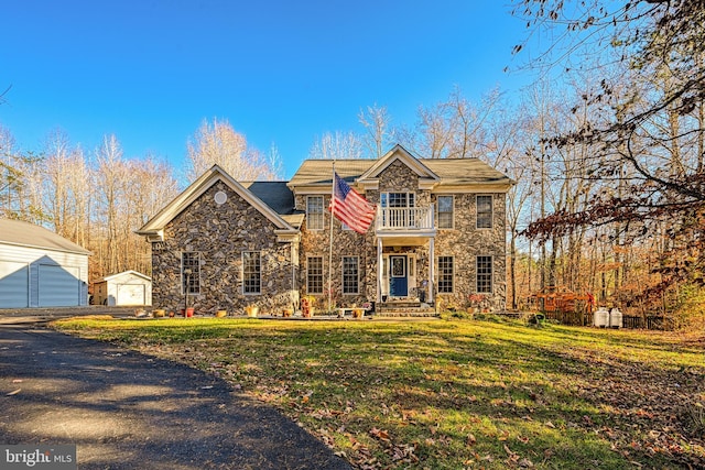 front facade with an outbuilding, a balcony, a garage, and a front yard