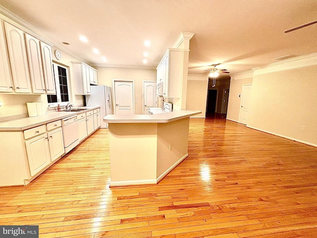 kitchen featuring white appliances, light wood-type flooring, kitchen peninsula, and crown molding