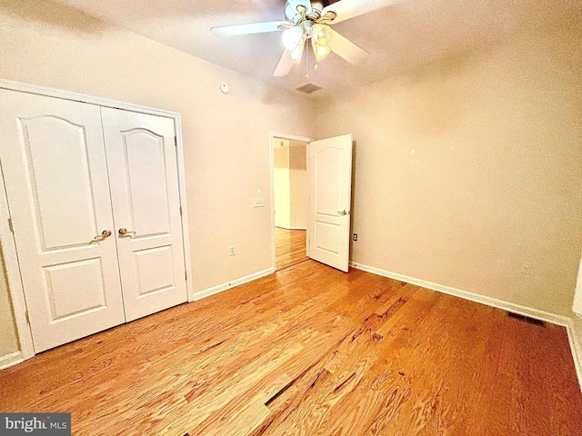 unfurnished bedroom featuring ceiling fan, light hardwood / wood-style floors, and a closet