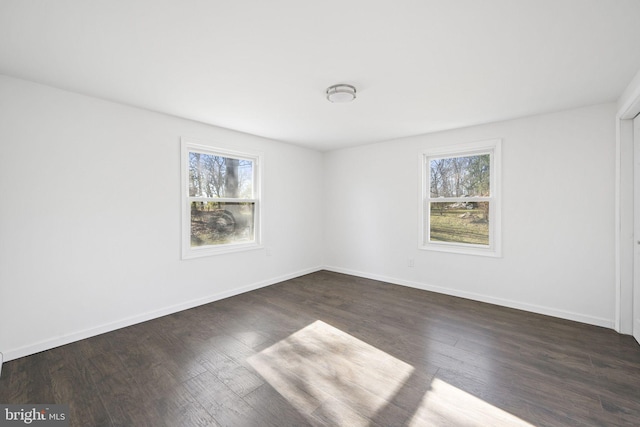 spare room featuring dark hardwood / wood-style floors and a healthy amount of sunlight