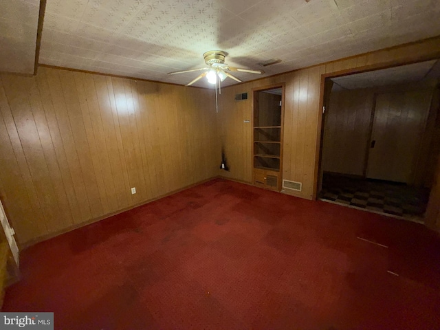 interior space featuring ceiling fan and wood walls