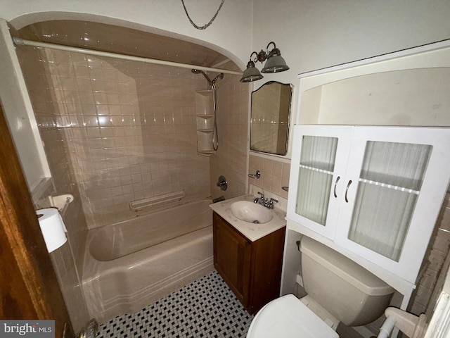 full bathroom featuring vanity, tiled shower / bath combo, and toilet