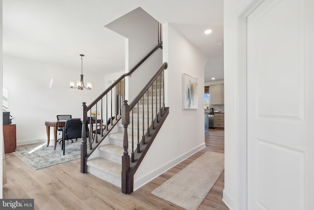 stairs featuring hardwood / wood-style floors and an inviting chandelier