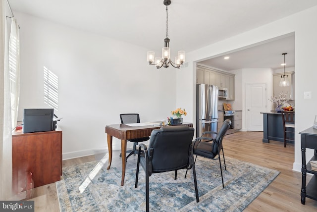 dining space with light hardwood / wood-style floors and an inviting chandelier