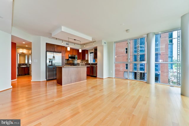 kitchen featuring appliances with stainless steel finishes, backsplash, pendant lighting, a center island, and light hardwood / wood-style floors