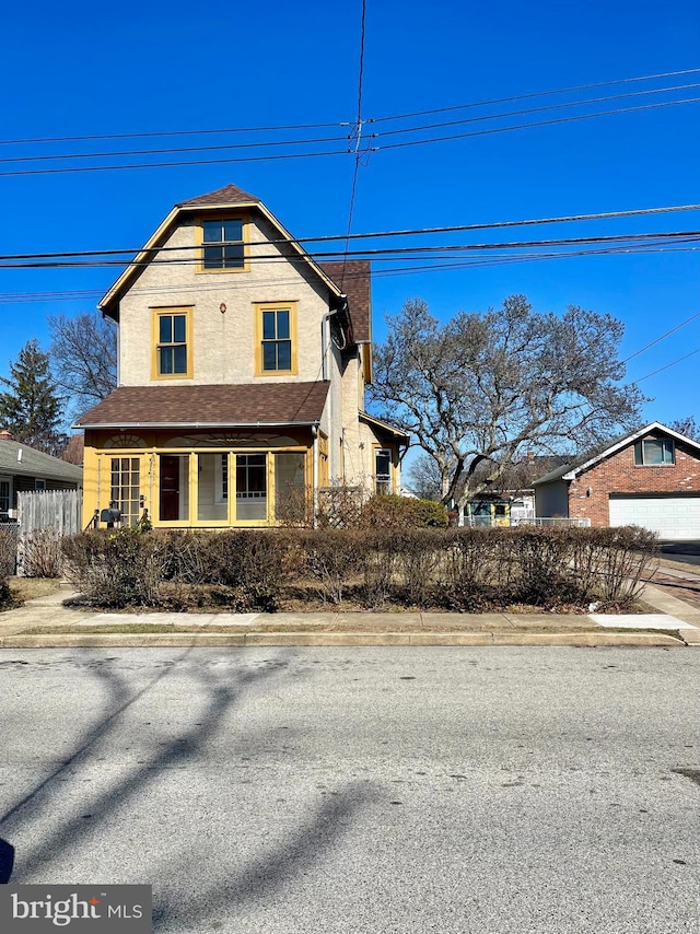 view of front facade featuring a shingled roof and fence