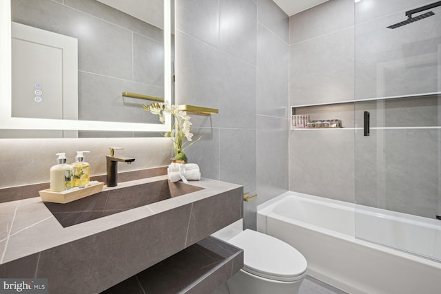 bathroom featuring toilet, sink, and tile walls