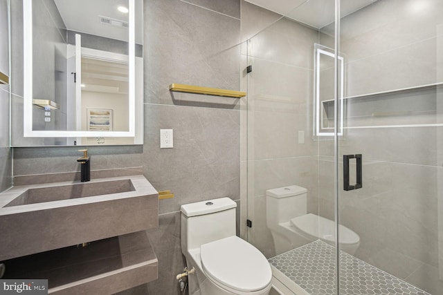 bathroom with an enclosed shower, vanity, toilet, and tile walls