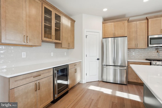 kitchen featuring tasteful backsplash, stainless steel appliances, beverage cooler, and light wood-type flooring