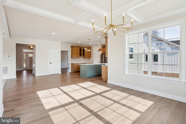 unfurnished living room with coffered ceiling, beamed ceiling, light hardwood / wood-style floors, and a chandelier