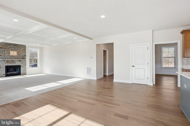 unfurnished living room featuring beam ceiling, coffered ceiling, a fireplace, and light hardwood / wood-style flooring