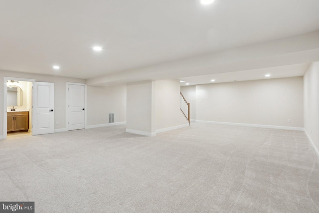 basement featuring sink and light carpet