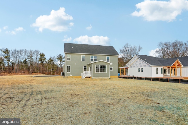 rear view of property with central air condition unit and a lawn