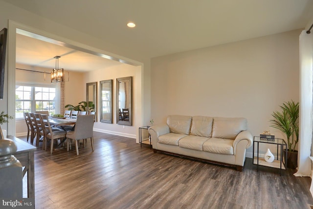 living room with dark hardwood / wood-style flooring and a notable chandelier