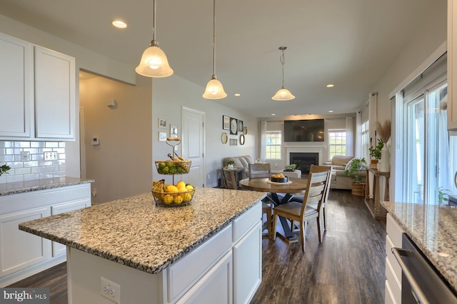 kitchen with pendant lighting, white cabinetry, decorative backsplash, a center island, and light stone counters