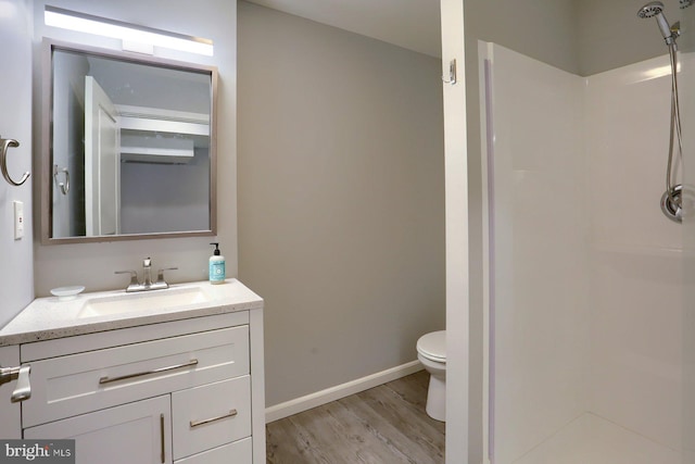 bathroom featuring a shower, hardwood / wood-style floors, vanity, and toilet