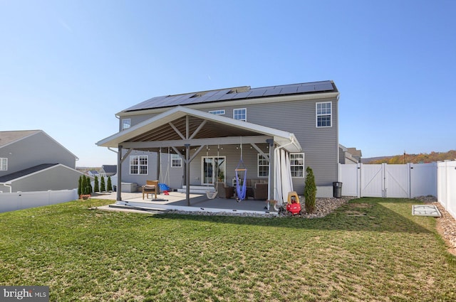 rear view of property with solar panels, a yard, and a patio area