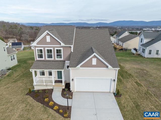 view of front of property featuring a mountain view, a porch, a garage, and a front yard