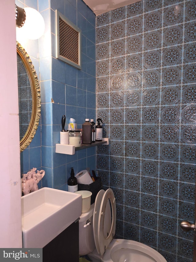 bathroom featuring toilet and tile walls