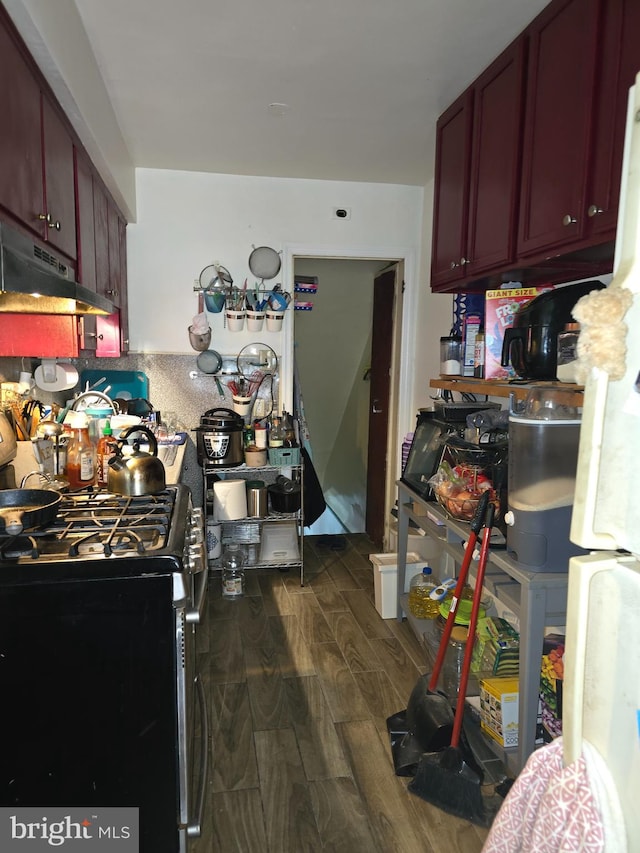 kitchen with black gas range oven, dark hardwood / wood-style flooring, and white fridge