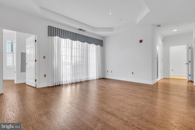 unfurnished living room with a tray ceiling, hardwood / wood-style floors, and a wealth of natural light