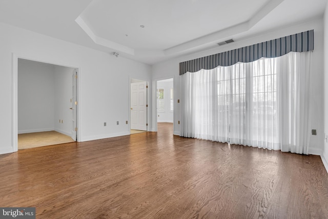 empty room with a raised ceiling and hardwood / wood-style floors