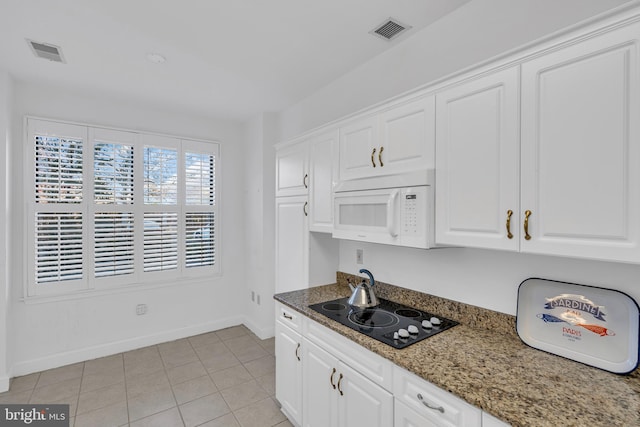 kitchen featuring black electric cooktop, light tile patterned floors, dark stone countertops, and white cabinets