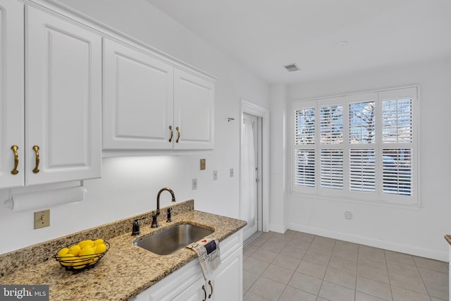 kitchen with white cabinetry, light stone countertops, sink, and light tile patterned flooring