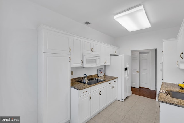 kitchen with dark stone countertops, white cabinets, and white appliances