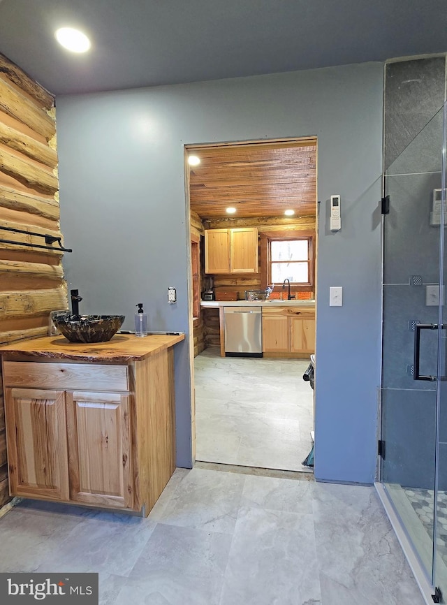 kitchen with dishwasher, wooden counters, rustic walls, and sink