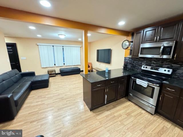 kitchen featuring tasteful backsplash, kitchen peninsula, stainless steel appliances, and light wood-type flooring