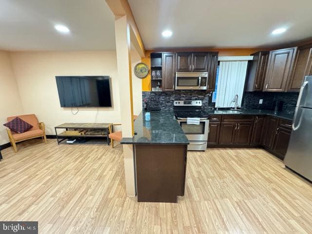 kitchen featuring tasteful backsplash, dark brown cabinets, stainless steel appliances, and light wood-type flooring