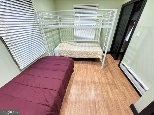 bedroom with hardwood / wood-style flooring and a baseboard heating unit